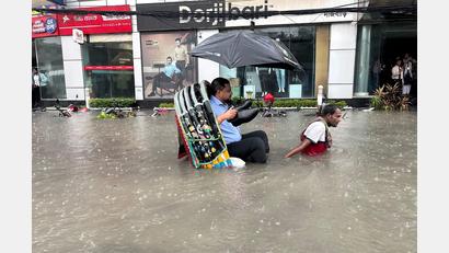 Bild: -/XinHua/dpa
Die Schuhe bleiben trocken: Ein Mann lässt sich in Bangladesch in einer Rikscha durch eine überflutete Straße fahren.