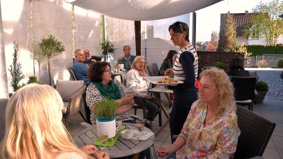 Bild: ubb
Nicole Punzmann (stehend) hat vor der offiziellen Eröffnung Freunden und Bekannten ihr neues Café vorgestellt.