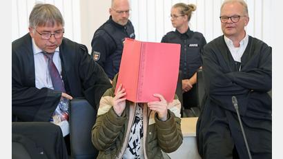 Bild: Bernd Wüstneck/dpa
Die Angeklagte sitzt mit Aktendeckel vor dem Gesicht zwischen ihren Verteidigern Andreas Ohm (l-r) und Thomas Löcker.