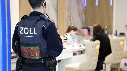 Symbolbild: -/dpa
Ein Zollbeamter steht bei einer Kontrolle in Köln in der Tür eines Nagelstudios. Im Landkreis Neustadt/WN haben Zöllner einen umfangreichen Fall von Schwarzarbeit, Mindestlohnverstößen und illegaler Beschäftigung in zwei Nagelstudios aufgedeckt.