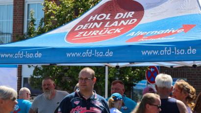Bild: Peter Gercke/dpa
„Hol dir dein Land zurück“, steht auf dem Schirm am Stand. Auf den Straßen in Sachsen-Anhalt hat die AfD inzwischen eine Menge Land erobert.