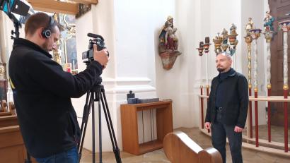 Bild: Dorothee Schulze Zumhülsen
Der Kunsthistoriker Daniel Rimsl berichtet in der Filmreihe „Schmuckstücke im Bistum Regensburg“ über die Prozessionsstangen in der Vilsecker Pfarrkirche (rechts hinter Rimsl).
