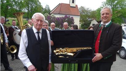 Bild: Houschka
Zu seinem 85. Geburtstag machte "Zur Linde"-Wirt Albert Graf (links) der Fensterbacher Jugendblaskapelle ein im Koffer überreichtes Saxofon zum Geschenk.. "Ein Gönner", wie Vereinsvorsitzender Markus Breitschaft (rechts) in seinen Dankensworten sagte.