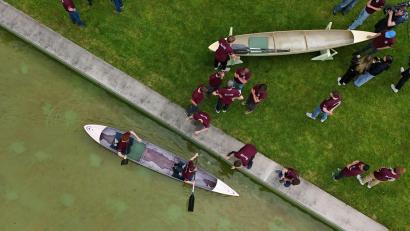 Bild: Martin Schutt/dpa
Studenten und Studentinnen der Bauhaus-Universität Weimar fahren mit dem Betonkanu auf dem Wasser im Weimarer Schwanseebad. (Aufnahme mit einer Drohne)