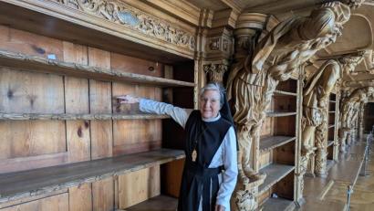 Bild: pz
In der Stiftsbibliothek zeigt Äbtissin M. Laetitia Fech auf einen der roten Punkte auf den Rückwänden der leeren Bücherregale. Damit sind besonders schadhafte Stellen markiert.
