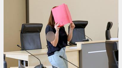 Bild: A7120 Bernd Wüstneck/dpa
Die Angeklagte betritt den Gerichtssaal mit rotem Aktendeckel vor dem Gesicht.