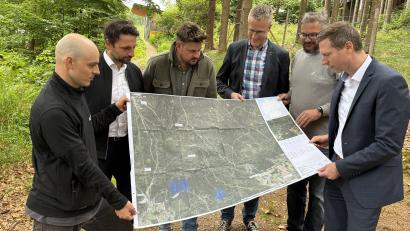 Bild: Hannes Huttinger 
Präsentieren am Ausgang des künftigen Flowtrails zur Bleaml Alm den Streckenplan zu Los 2 (von links): Urban Niedermayr (Firma Allegra), die Bürgermeister Sebastian Zwenzner (Warmensteinach), Sebastian Voit (Fichtelberg) und Michael Schreier (Bischofsgrün) sowie Zweckverbandsgeschäftsführer Markus Döhla und Landrat Florian Wiedemann.