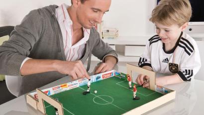 Bild: DIY Academy/tesa
Das Spielfeld lässt sich mit wenigen Materialien aus einem stabilen Pappkarton, etwas Bastelmaterial und Tipp-Kick-Figuren selbst bauen.