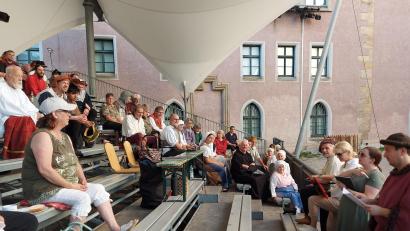 Bild: Georg Lang
Bei den Proben ist die Zuschauertribüne der Besprechungsort der Spieler mit der Leitung des Festspielvereins (Manuel Winkler) und der Regie (Verena Hergl und Karin Michl) (von rechts). Im Hintergrund das historische Pfalzgrafenschloss als authentischer Spielort.