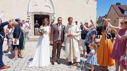 Bild: Oswald Zintl
Durch ein langes Spalier schritten Sophia Wollner und Michael Schels nach der Trauungszeremonie. Mit im Bild ist Pfarrer Gregor Schweizer.