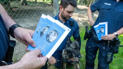 Bild: Armin Weigel/dpa
Polizeibeamte informieren Spaziergänger  in einem Wald mit Infomaterial über Maßnahmen gegen Straftaten an Wildtieren.