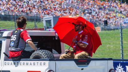 Bild: Philipp von Ditfurth/dpa
Die Ferrari-Fahrer Charles Leclerc (links) und Lewis Hamilton schützen sich im Vorjahr mit einem Schirm und einer Kühlweste vor der Hitze. Auch am Wochenende wird es in Spielberg heiß. (Archivbild)