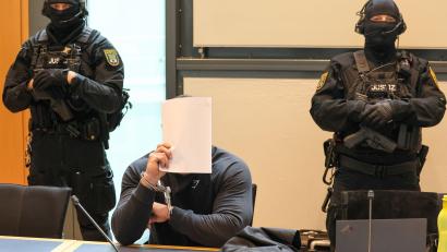Bild: Peter Gercke/dpa
Der Angeklagte sitzt im Gerichtssaal des Landgerichts Magdeburg zwischen zwei Justizbeamten.