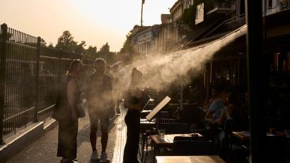 Bild: Petros Giannakouris/AP/dpa
Ein Touristenpaar geht an einer Sprühanlage vorbei, während ein Restaurantmitarbeiter sie im Athener Stadtteil Monastiraki zu ihrem Tisch führt.