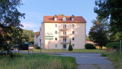 Bild: as
Im ehemaligen Schlosshotel Ernestgrün ist wieder Leben eingekehrt. Seit Mitte Juli künden Autokennzeichen aus ganz Deutschland auf dem Parkplatz von regem Betrieb im Bau aus den 1980er Jahren und der neuen Orangerie (rechts).