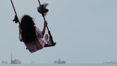 Bild: Razieh Poudat/ISNA/AP/dpa
Ein Mädchen schaukelt am Ufer, während Frachtschiffe und andere Handelsschiffe in der Straße von Hormus vor Anker liegen. (Archivbild)