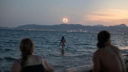Bild: Clara Margais/dpa
Eine Frau badet im Meer und weitere beobachten die totale Sonnenfinsternis am Strand von Palma.