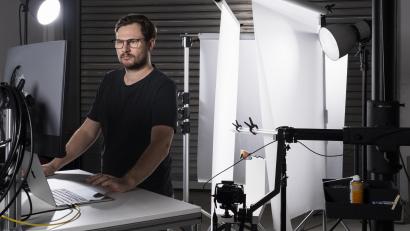 Bild: Johannes Zrenner
Johannes Zrenner am Arbeitsplatz im eigenen Studio: Im Hintergrund ist ein Produkt-Set zu sehen, in dessen Mittelpunkt eine Sportbrille steht.
