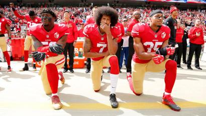 Bild: John G Mabanglo/EPA/dpa
Colin Kaepernick (Mitte) kniend bei der Nationalhymne. Er bekam Unterstützung einiger Mitspieler, am Ende war es aber auch seine letzte Saison in der NFL. (Archivfoto)