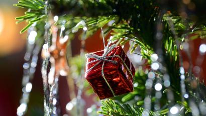 Bild: Jens Kalaene/dpa
Ein kleines rotes Geschenkpaket als Weihnachtsbaumanhänger und Lametta hängen an einem Weihnachtsbaum.