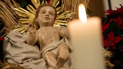 Bild: Sven Hoppe/dpa
In einer Krippe liegt eine Holzfigur von Jesus. Daneben brennt eine Kerze.