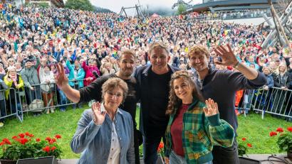 Bild: Peter Kneffel/dpa
Die Schauspieler Monika Baumgartner (l-r), Mark Keller, Hans Sigl, Ronja Forcher und Frederic Brossier stehen beim „Bergdoktor-Bergfest“ vor großem Publikum.