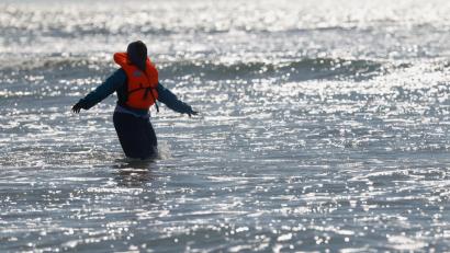 Bild: Jean-Francois Badias/AP/dpa
Ein Migrant läuft in Nordfrankreich im Meer nahe der Küste, während er versucht, den Ärmelkanal mit einem Schlauchboot von Frankreich nach Großbritannien zu überqueren.