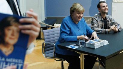 Bild: Carsten Koall/dpa
Merkel signiert Kunstpostkarten im Bode-Museum neben dem Maler ihres dort ausgestellten Porträts, Jérémie Queyras.