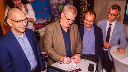 Foto: www.fotoschmiede-mcb.de
Schwandorfs Oberbürgermeister Andreas Feller (Zweiter von links) unterzeichnet die Vereinbarung für die Patenschaft der Stadt Schwandorf beim Regensburger Weihnachtssingen 2026.