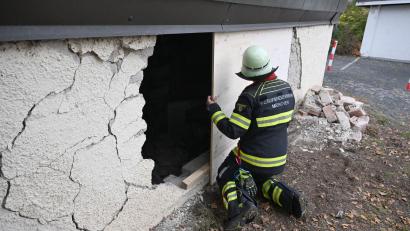 Bild: Felix Hörhager/dpa
Ein Feuerwehrmann deckt das Loch in der Garagenwand ab.