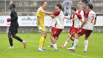 Bild: Hubert Ziegler
Jubel bei den Spielern des SSV Jahn Regensburg nach dem von Torhüter Julio Peutler gehaltenen Foulelfmeter, während der Gebenbacher Elfmeterschütze Jeanpaul Uzuamaka Ajala-Alexis (ganz links) enttäuscht davonschleicht. 
DJK Gebenbach - SSV Jahn Regensburg II 1:6