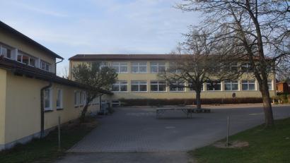 Bild: Ernst Frischholz
Grundschule Püchersreuth (hintern) mit der Turnhalle (links). Ihr gegenüber soll parallel zum TSV-Sportplatz das Gebäude für die Ganztagsbetreuung errichtet werden. Durch diese Dreiseitformation würde ein Innenhof entstehen.