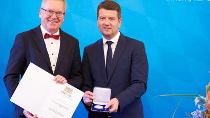 Bild: Bayerisches Innenministerium / Matthias Pfützner
Innenstaatssekretär Sandro Kirchner (rechts) verleiht die Kommunale Verdienstmedaille in Silber an Michael Cerny.