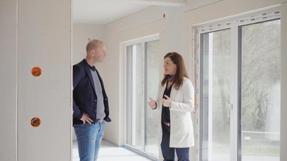 FischerHaus-Geschäftsführerin Barbara Fuchs (r.) und „Baureisebegleiter“ Marco Werner erläutern, wie im Baugebiet Mendorferbuch binnen kürzester Zeit zwölf FischerHäuser in die Höhe wachsen. Bild: Fuchs &amp; Söhne